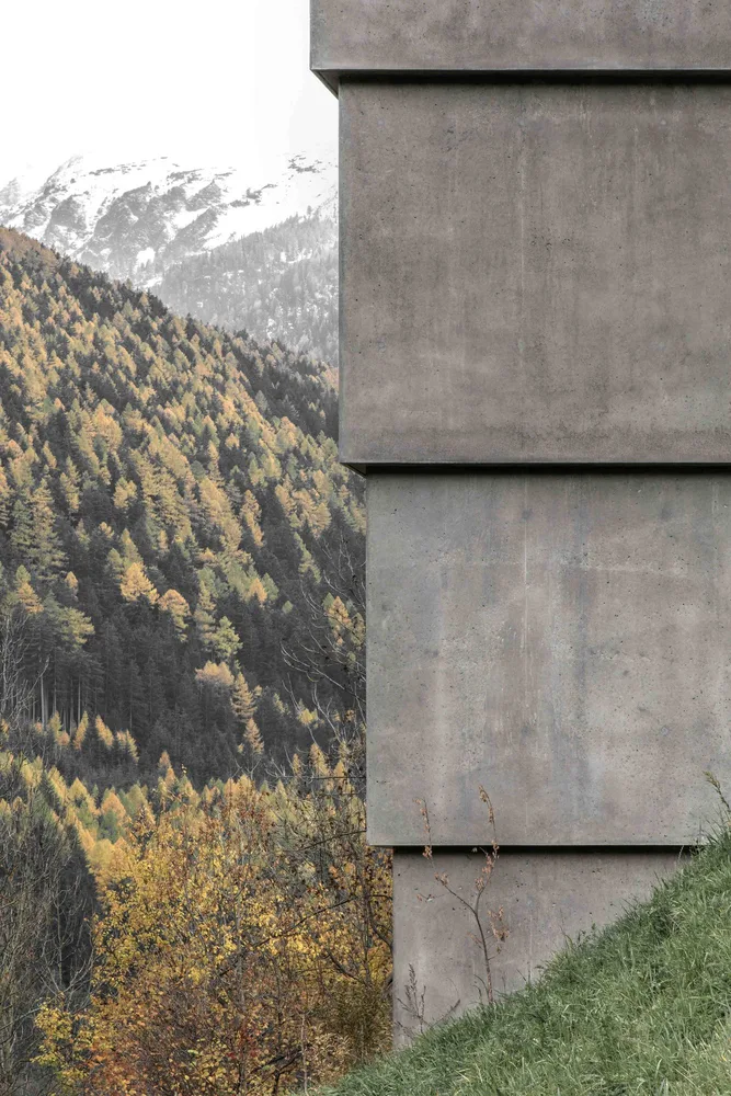 Betonelement mit alpiner Landschaft im Hintergrund
