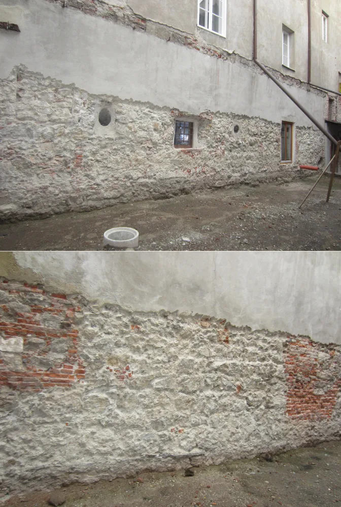Weiße alte Steinmauer, unverputzt,mit Fenstern und Durchbrüchen