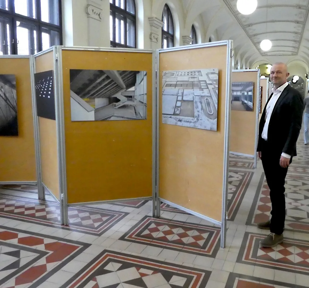 Fotograf und Architekt Klaus Grill neben Fotos in historischem Innenraum, Graz, 2025