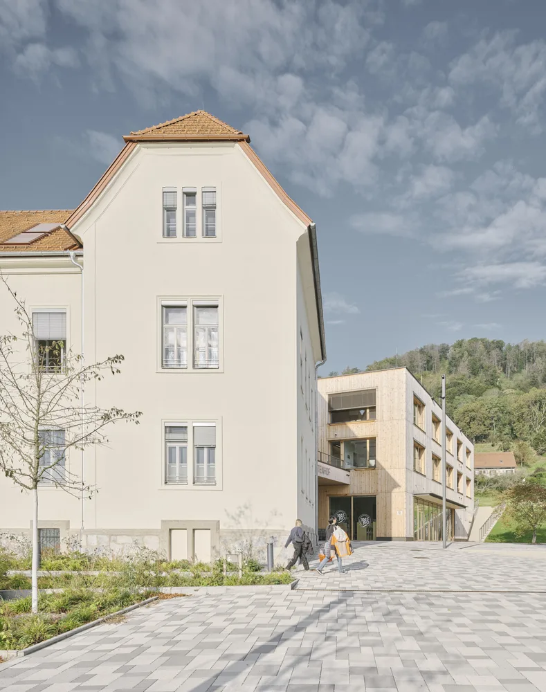 Photographie eines mehrgeschossigen Schulbaus, im Vordergrund ein älterer Bauteil, im Hintergrund ein neuer