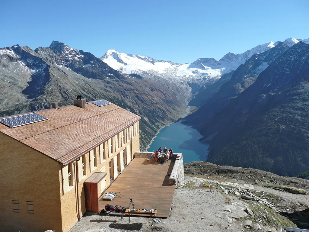 Eine Berghütte, im Hintergrund ein Tal mit See