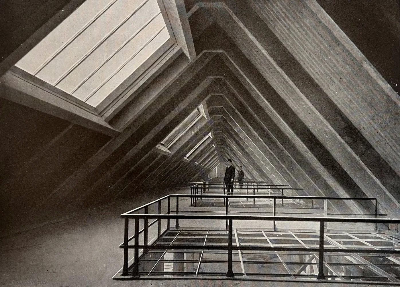 Historische Ansicht in Schwarzweiß eines sehr großen Dachraumes im Rohbau in Beton mit großformatigen Fenstern auf der linken Seite, die sehr viel Tageslicht einlassen.