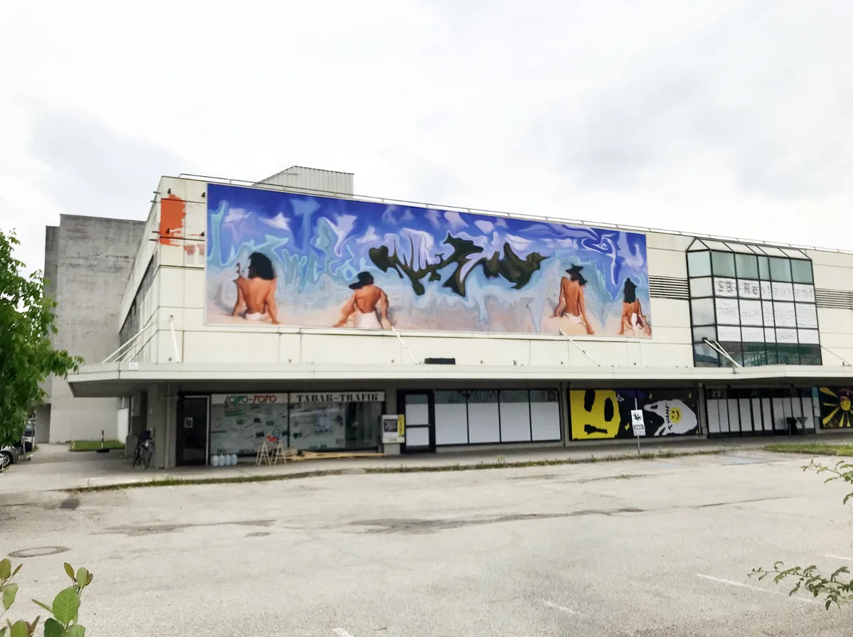 © Christoph Wiesmayr Gewerbebau mit buntem Wandgemälde auf dem vier mesnchliche Oberkörper abgebildet sind, FMR Festival Linz, 2024, Foto: C. Wiesmayr