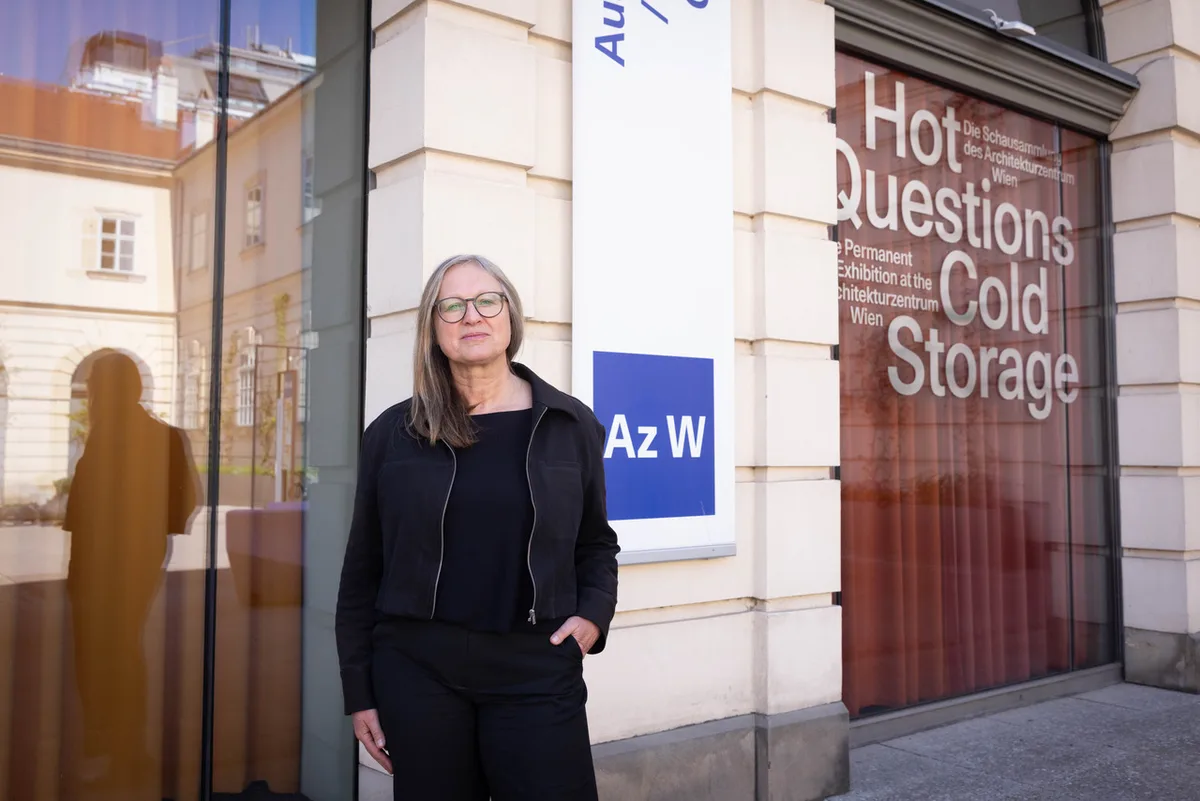 Porträt einer Frau, im Hintergrund ein gelbes Gebäude