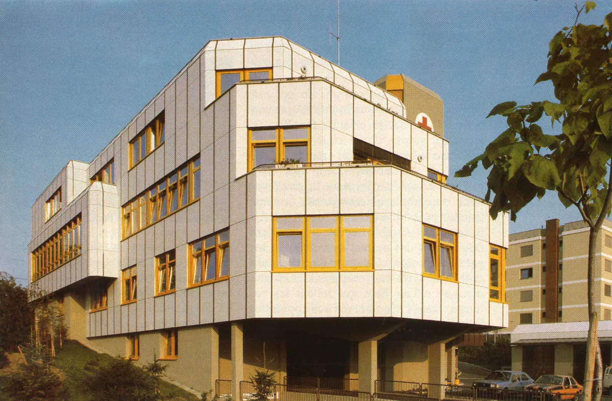 Foto eines mehrgeschossigen Gebäudes mit weißer Fassade und gelben Fenstern