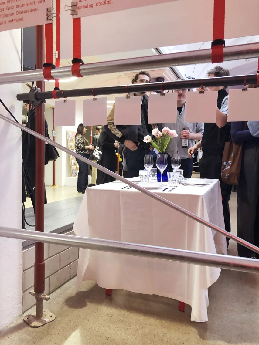 Gedeckter Tisch mit Blumen hinter Gerüst, banale potenziale, Ausstellung HDA, 2025, © sv