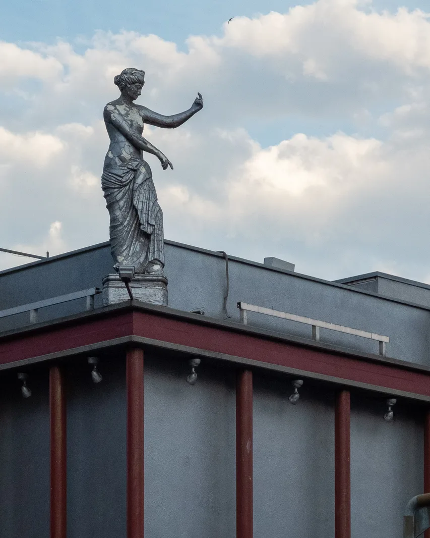 Antike Figur auf dem Dach eines blau-roten Gebäudes