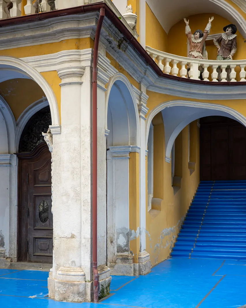Ein gelb-weißes Gebäude, Boden mit blauem Filzteppich überdeckt