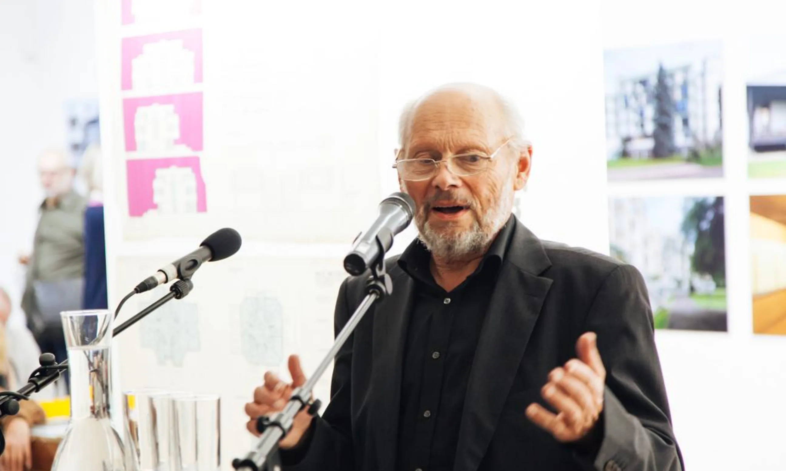 Ein älterer Mann spricht in zwei Mikrofone