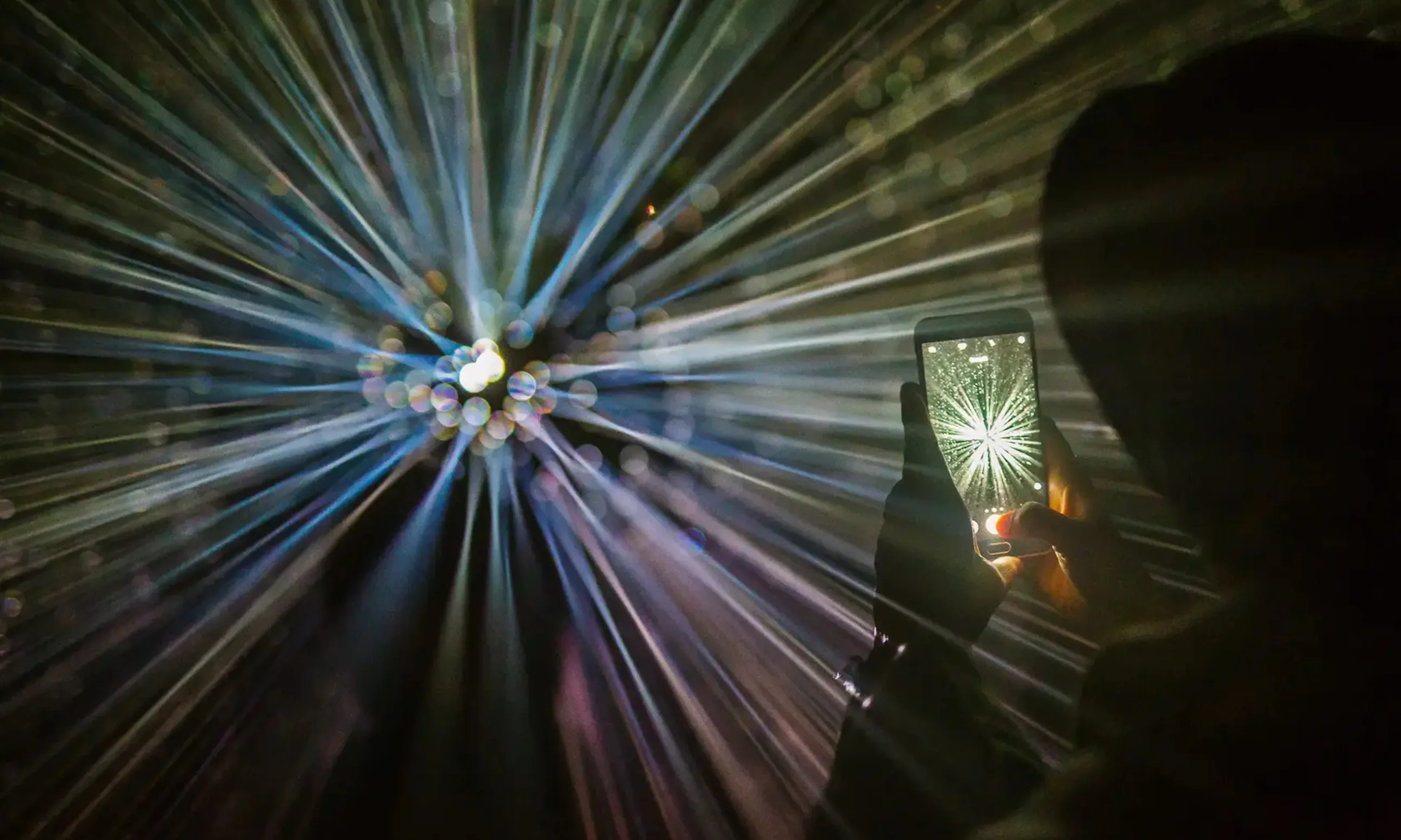 Bunte Lichtstrahlen und Person mit Handy