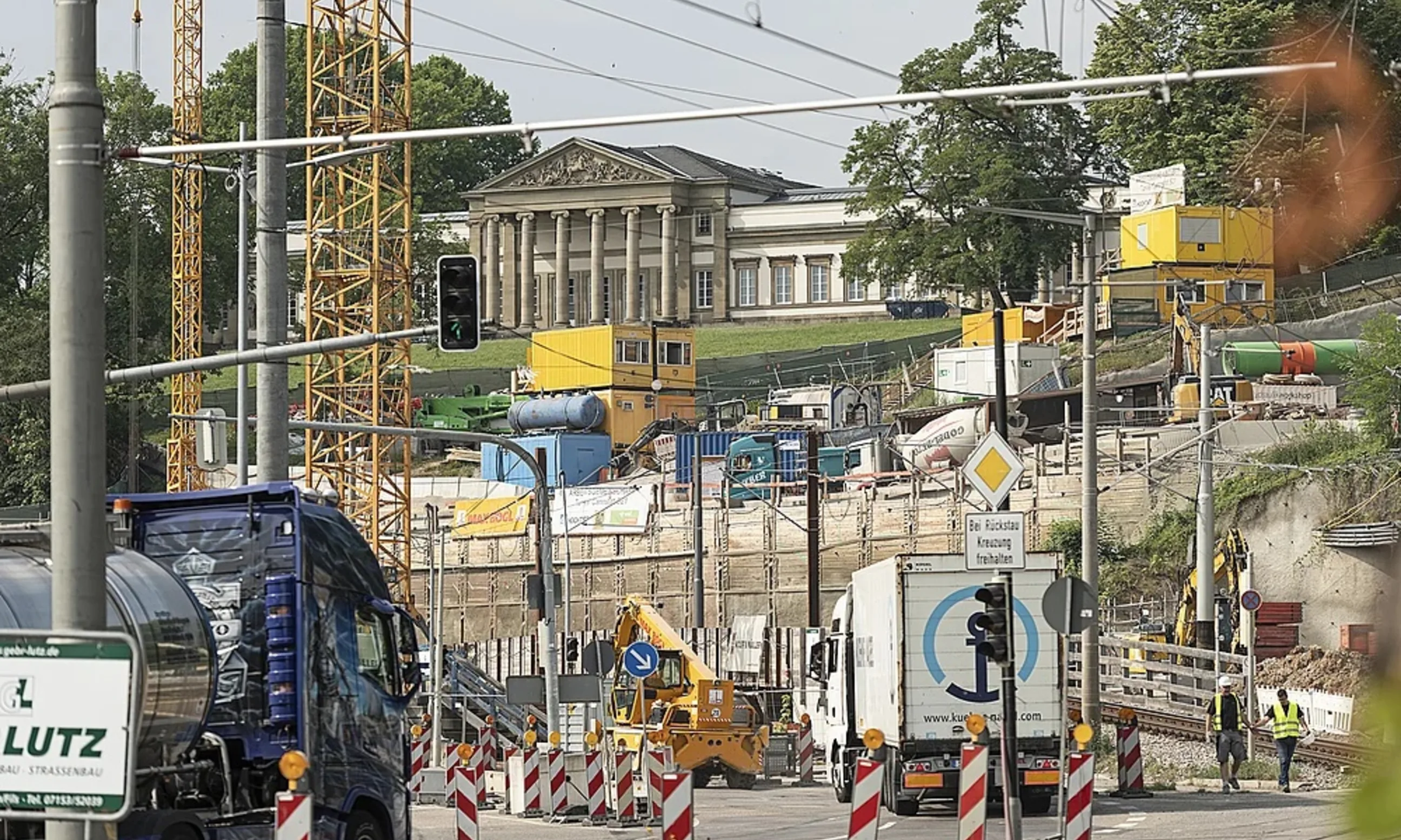 Baustellenfahrzeuge auf der Straße, erhöht im Hintergrund ein Schloss
