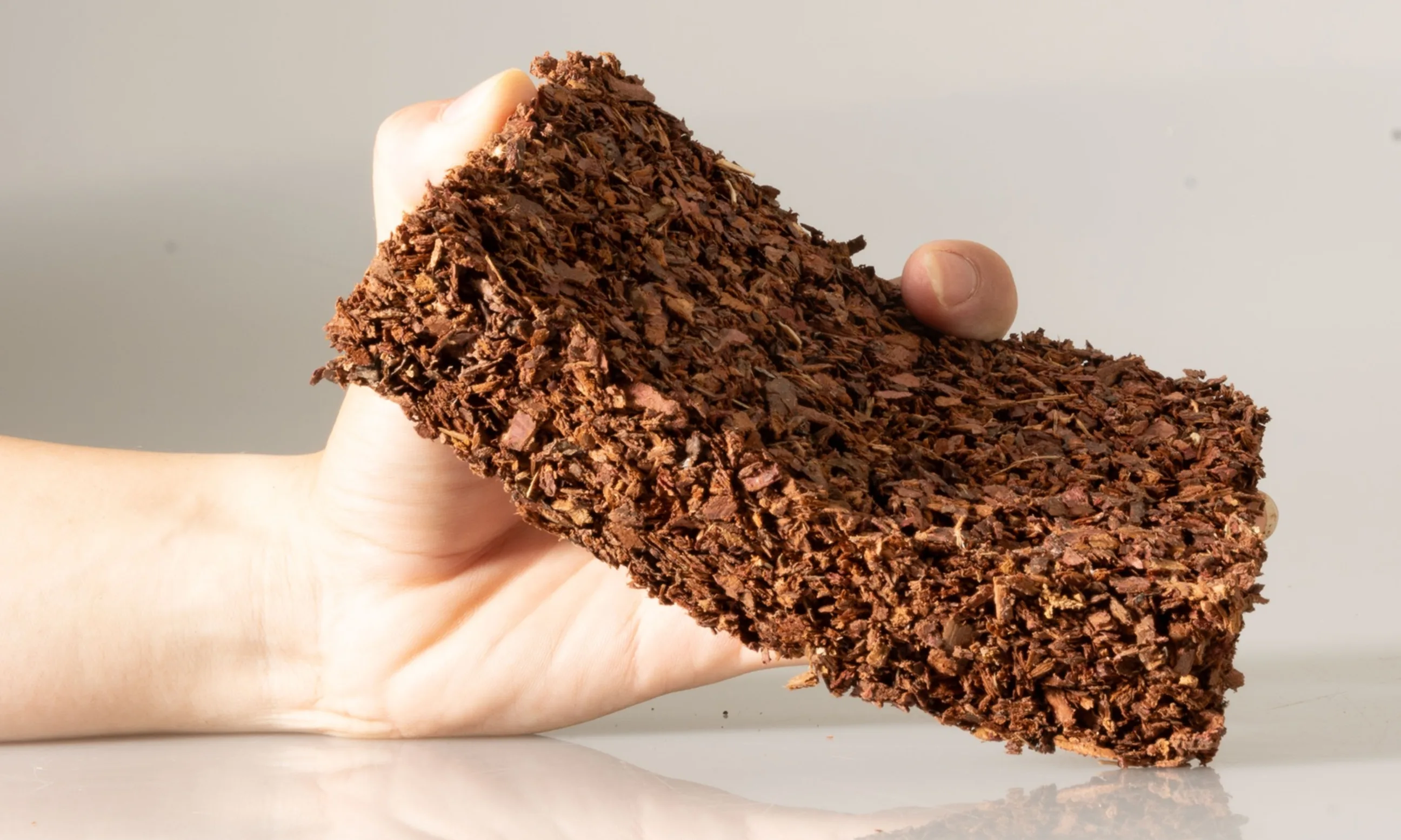 Hand hält braunes Material in Form eines Rechteckes