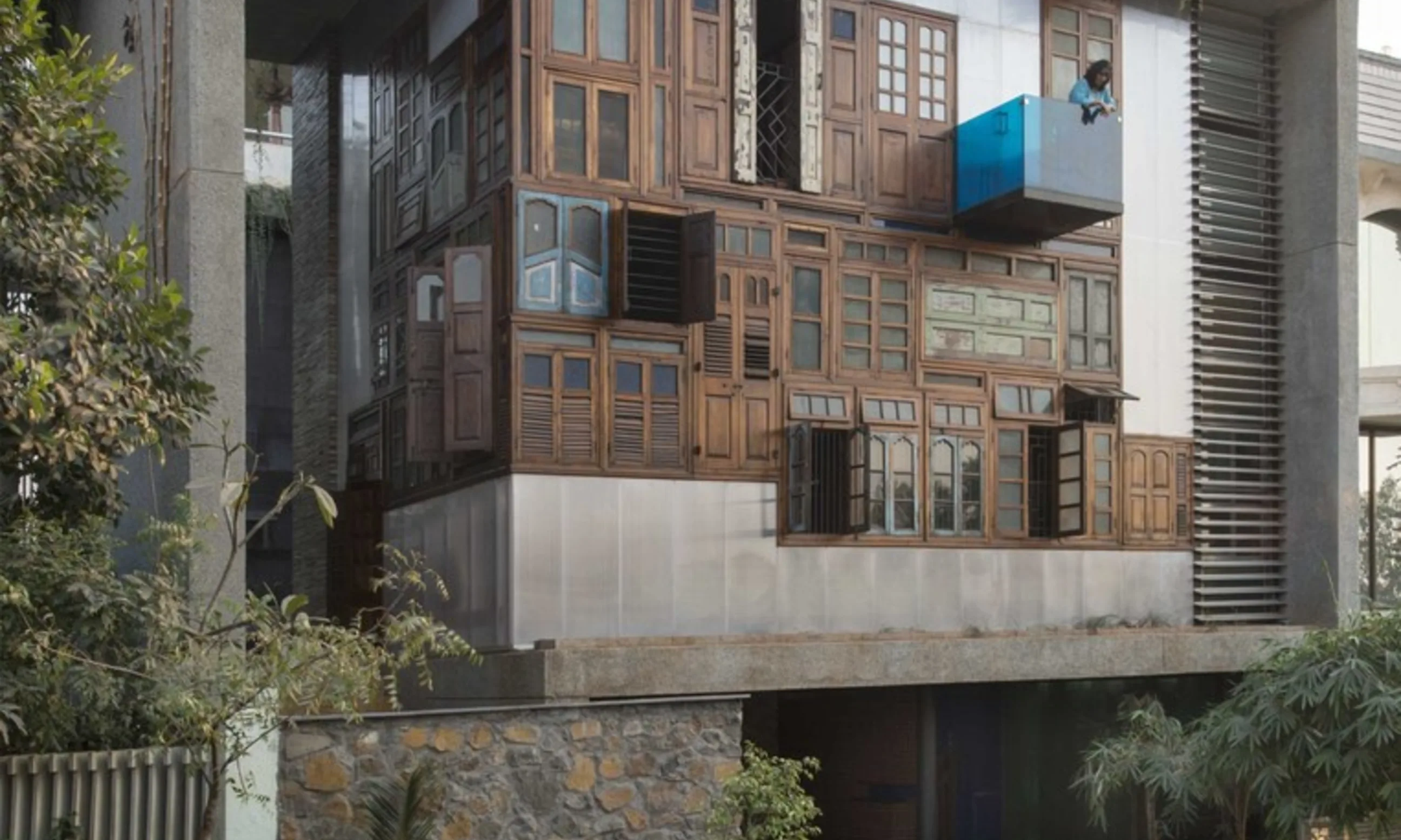 Haus aus Beton und Holzelementen, umrandet von vielen Pflanzen