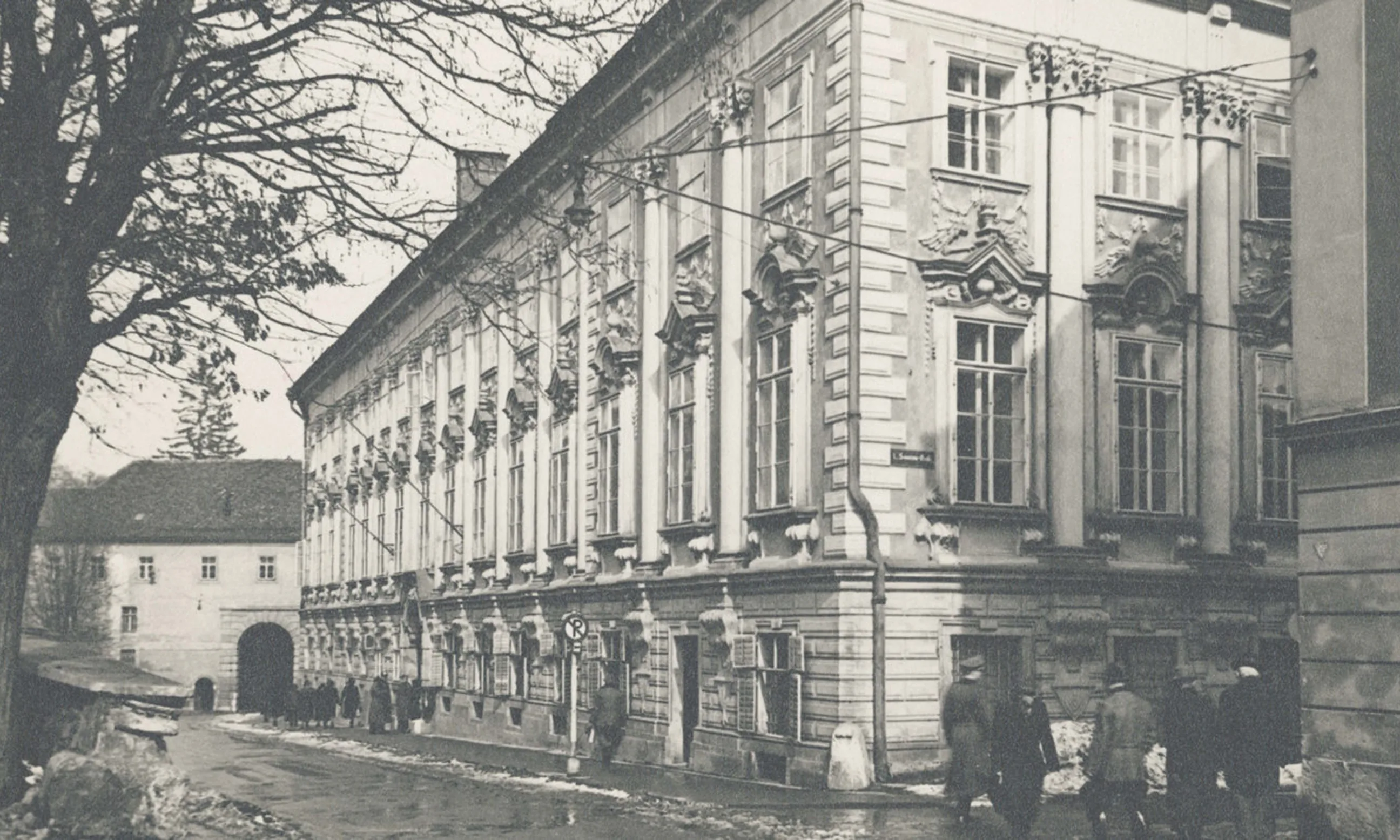 Straße mit einem barocken Gebäude im Vordergrund, schwarz-weiß