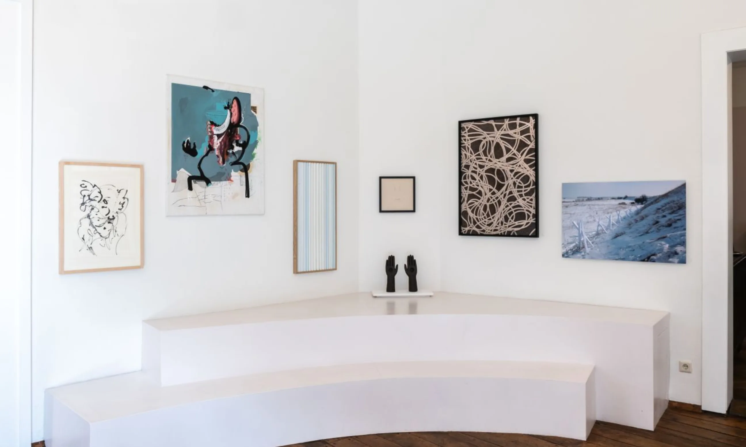 Ecke eines Raumes mit sechs Objekten an der Wand und auf einer Erhöhung des Bodens