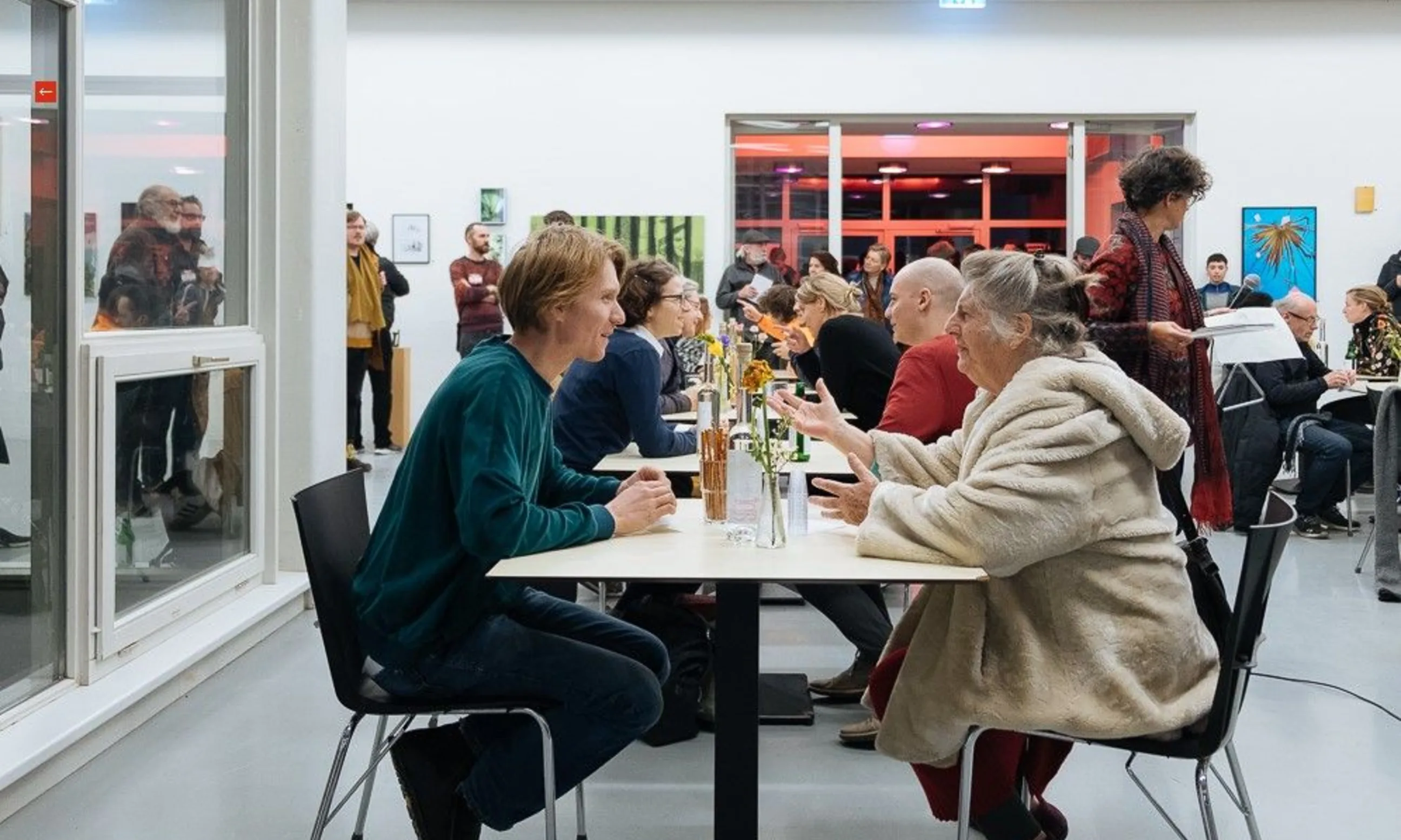 Gruppe an Tischen sitzender Menschen, im Gespräch