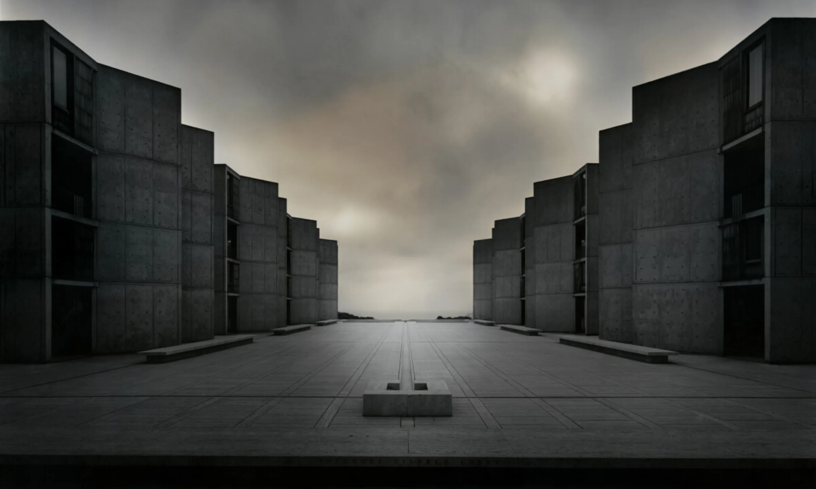 Innenhof eines Gebäudes, links und rechts Gebäude aus Rohbeton, am Horizont grauer Himmel