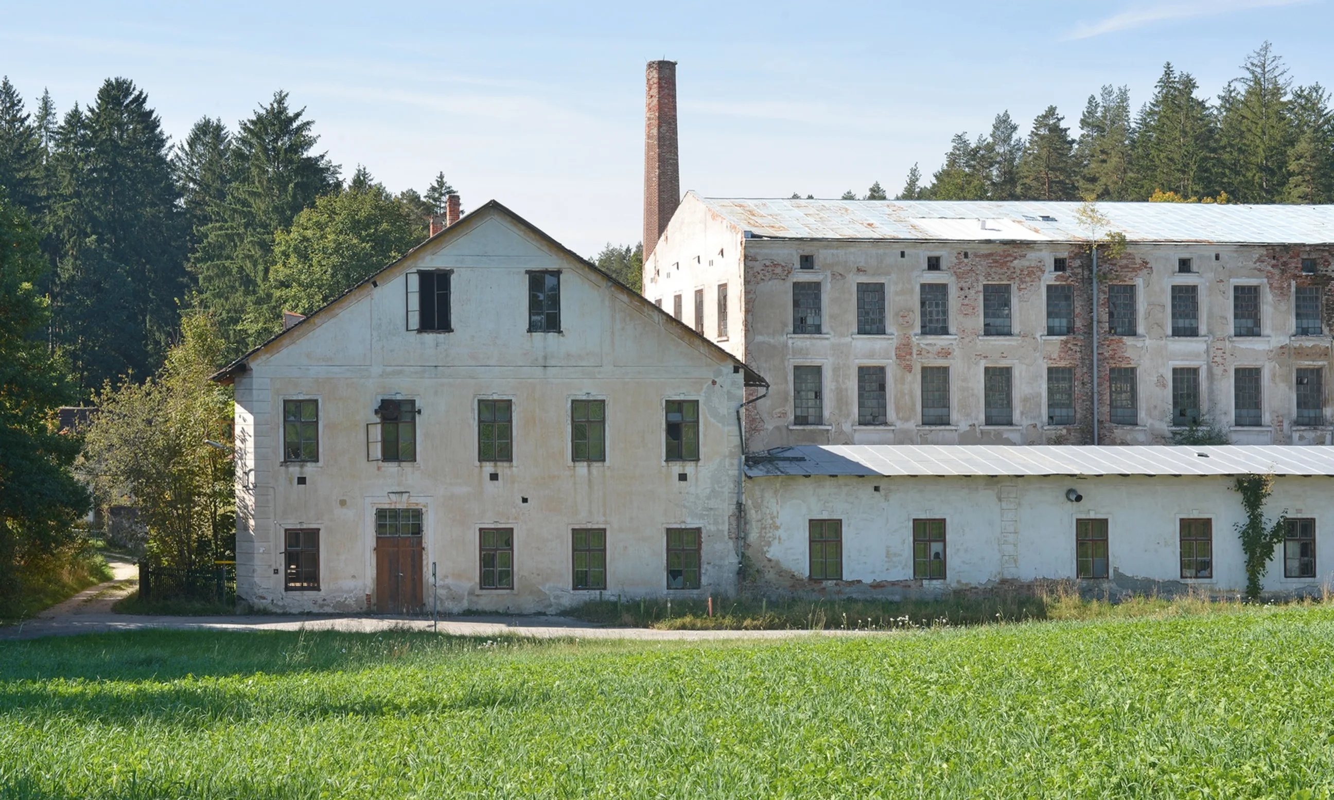 Verlassenes Industriegebäude, im Hintergrund eine Waldlandschaft