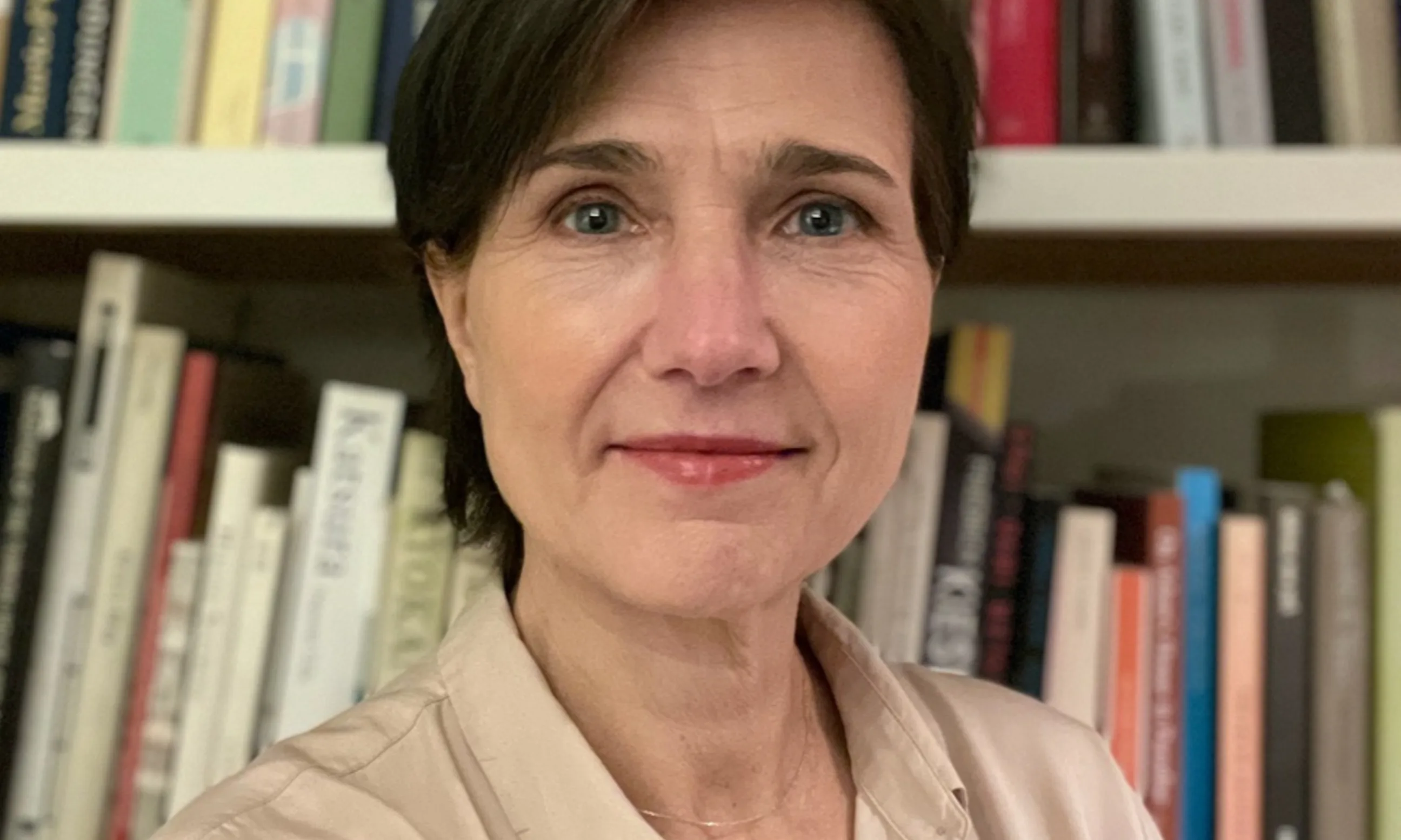 Porträt einer Frau, im Hintergrund ein Bücherregal