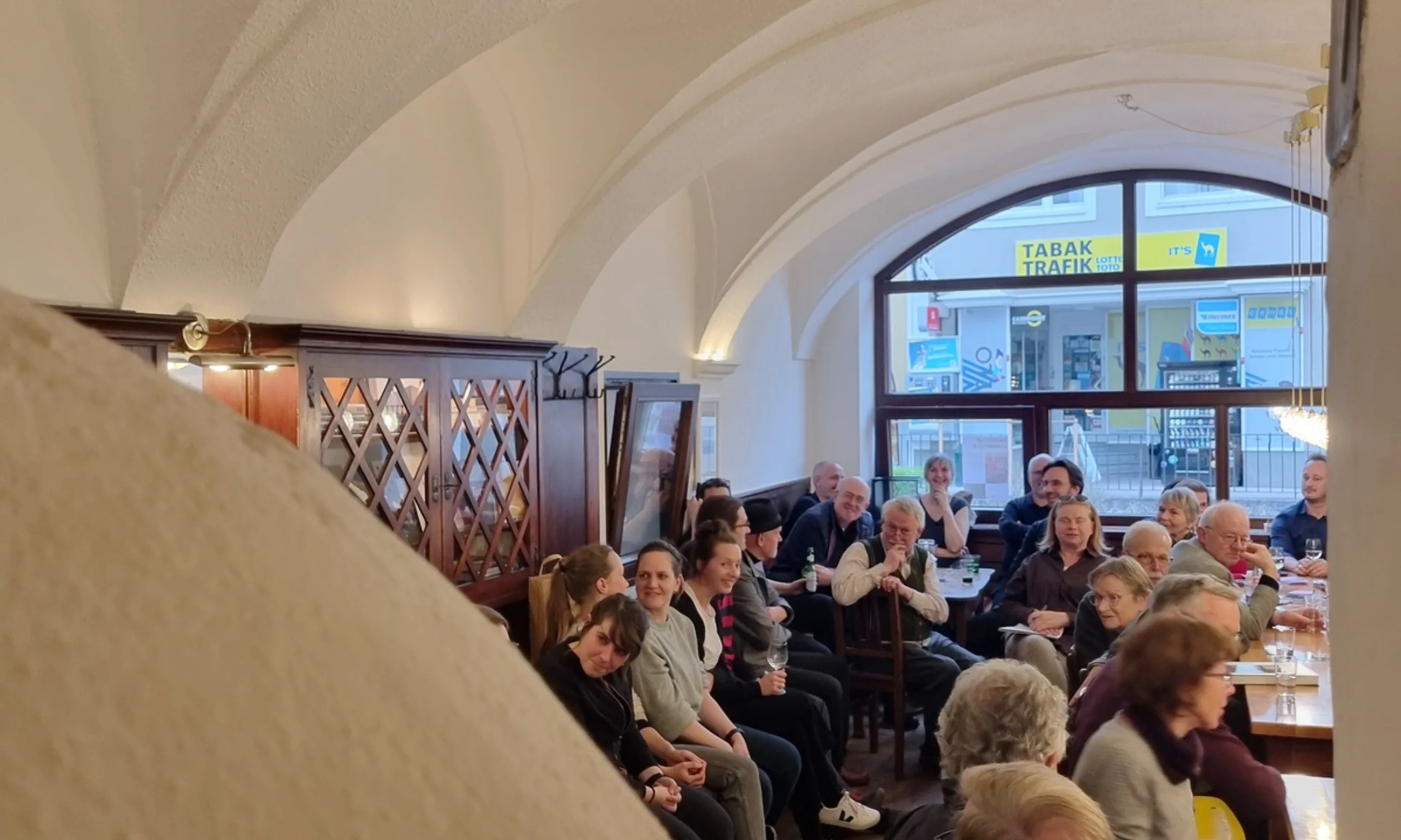 Eine Gruppe an Menschen sitzend in einem Innenraum mit Doppelgewölbe