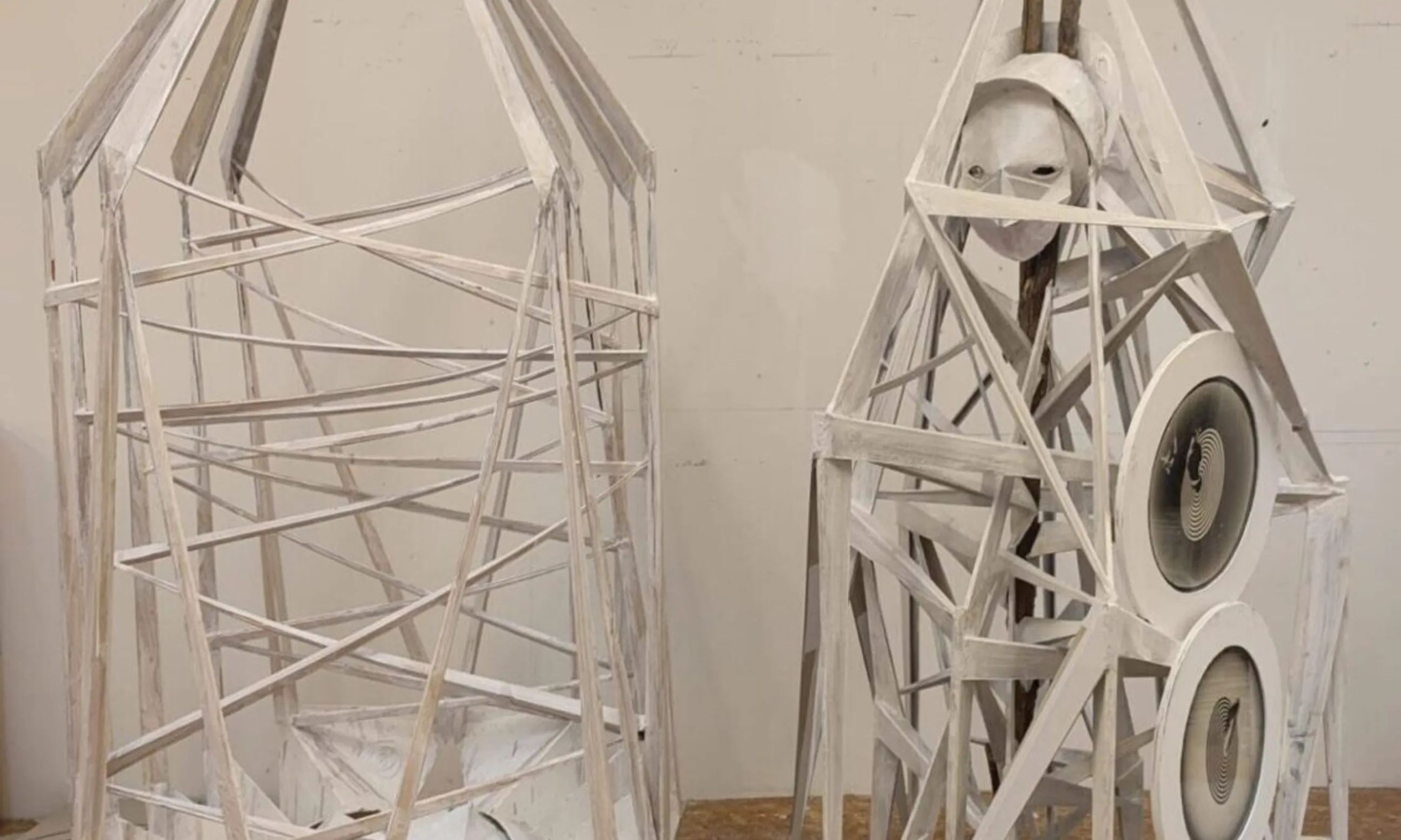 Zwei weiße Skulpturen auf einem Holzboden