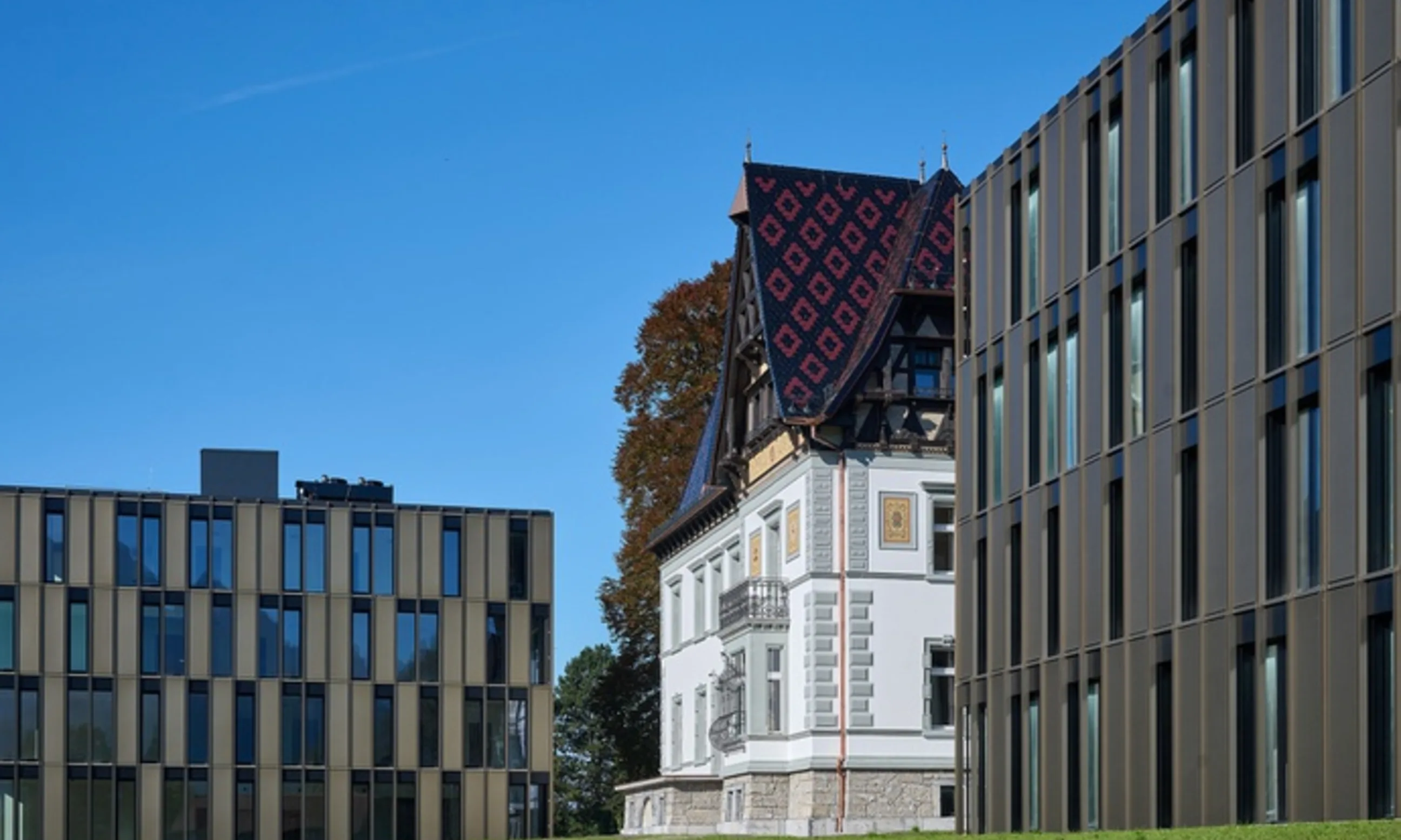 Eine alte Ville mit Giebeldach zwischen zwei Neubauten mit Stahl-Glas-Fassade