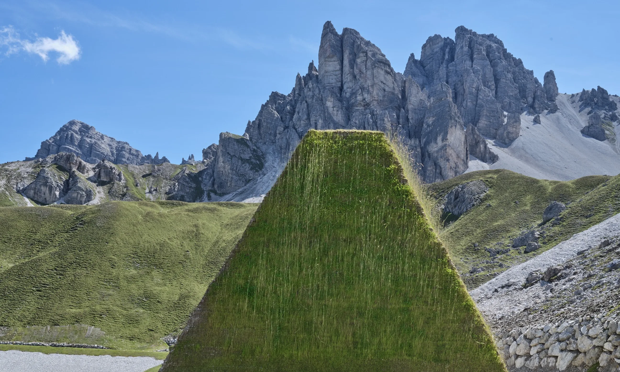 Zwei Schafe spazieren an einem Grashaufen vorbei, im Hintergrund eine alpine Landschaft