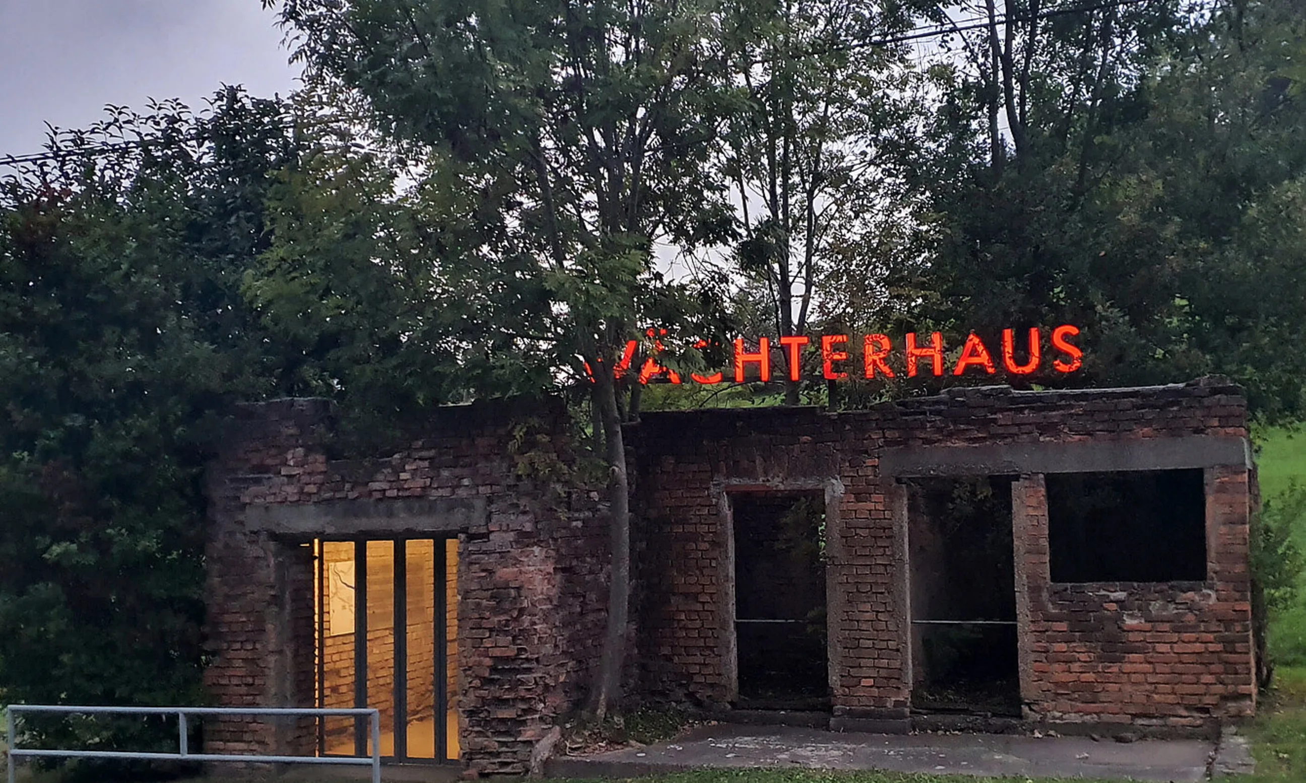 Bild eines Klinkergebäudes, am Dach Leuchtschrift mit dem Text "Wächterhaus"