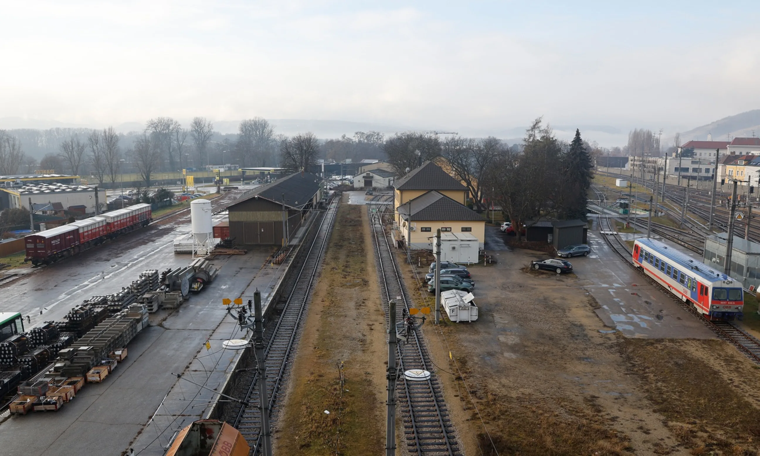 Vogelperspektive auf einen Frachtenbahnhof: mehrere Züge, viele Schienen, dazwischen vereinzelt Grüngewächse