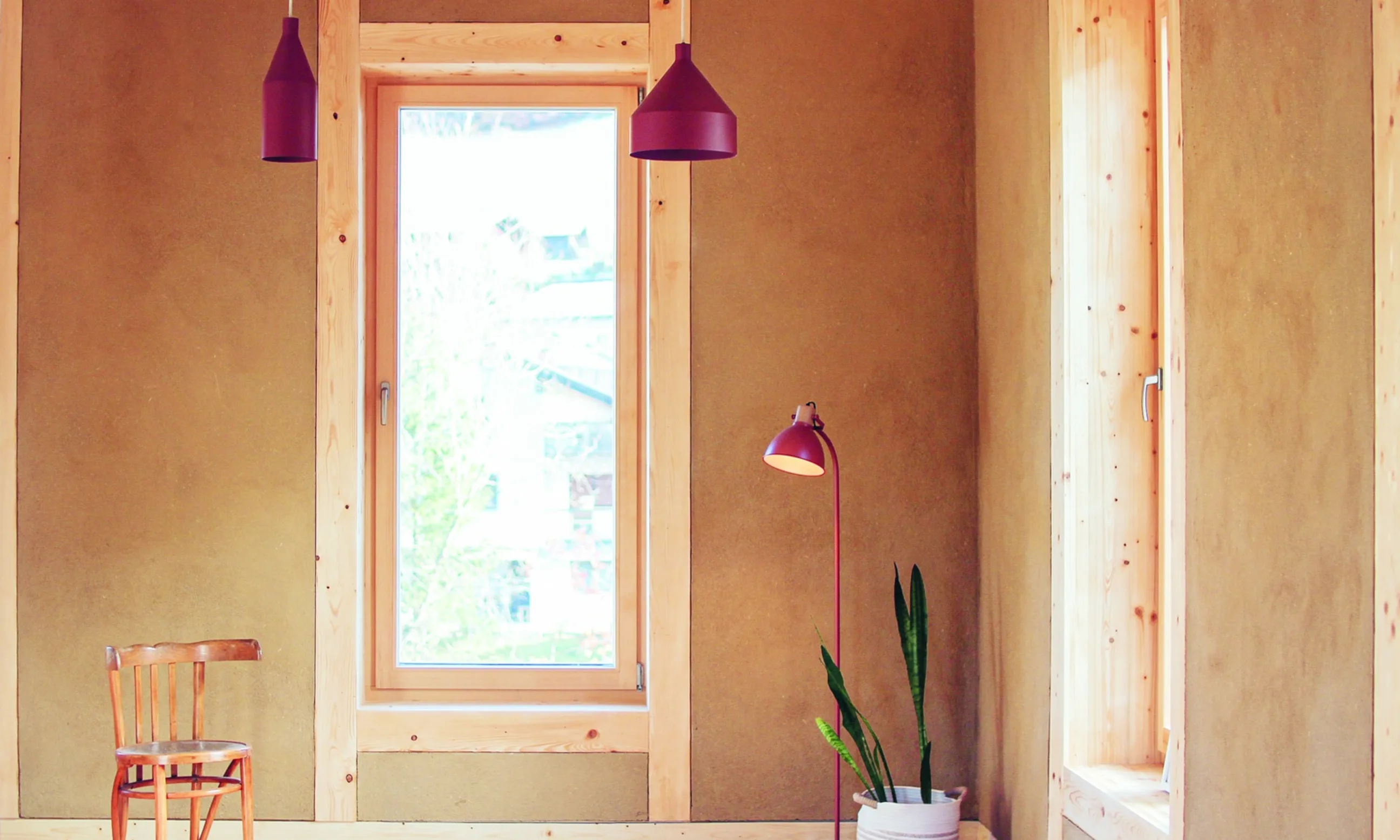 Photographie eines Innenraumes mit Lehmoberflächen und einem Fenster mittig