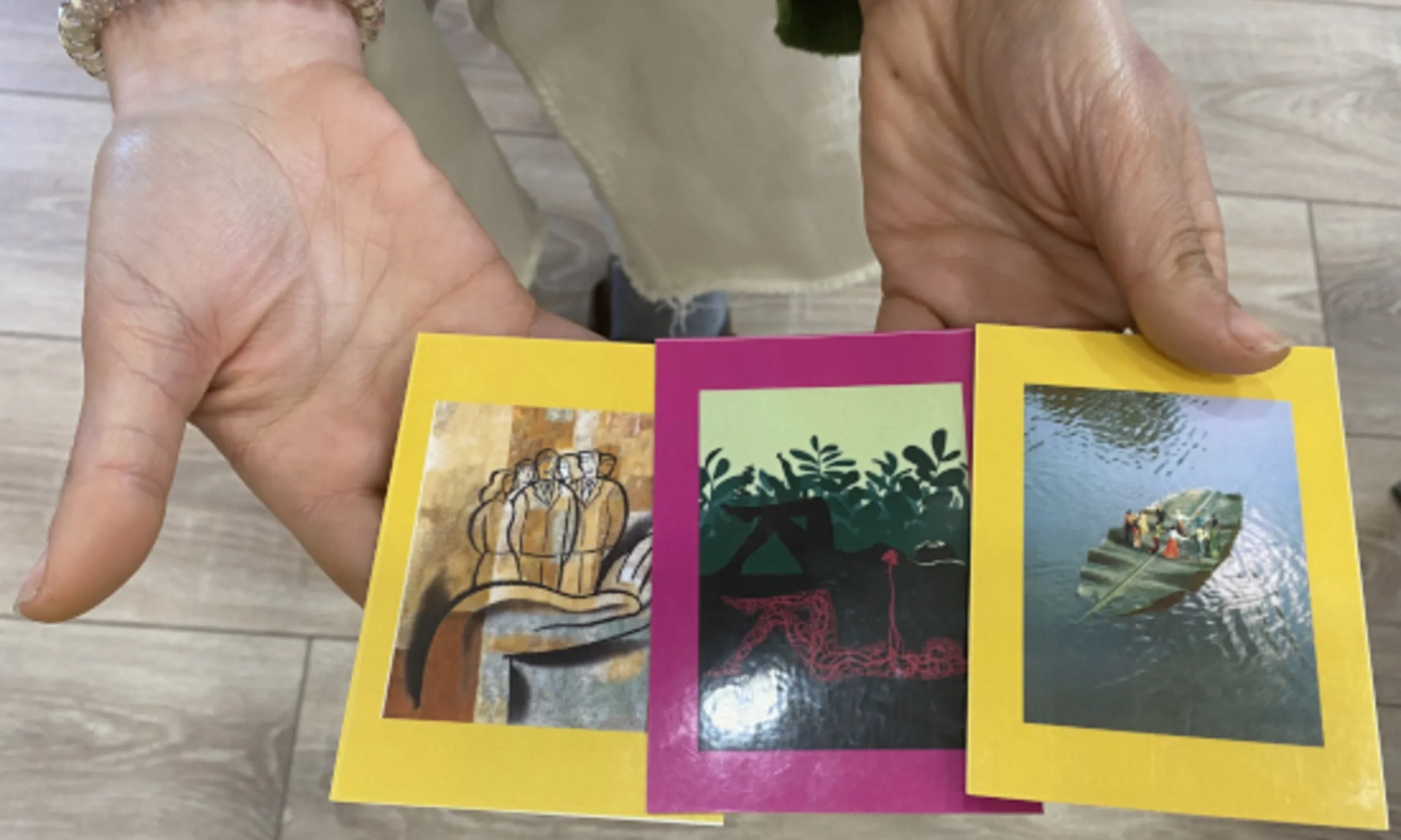 Zwei Hände halten drei bunte Karten in der Hand
