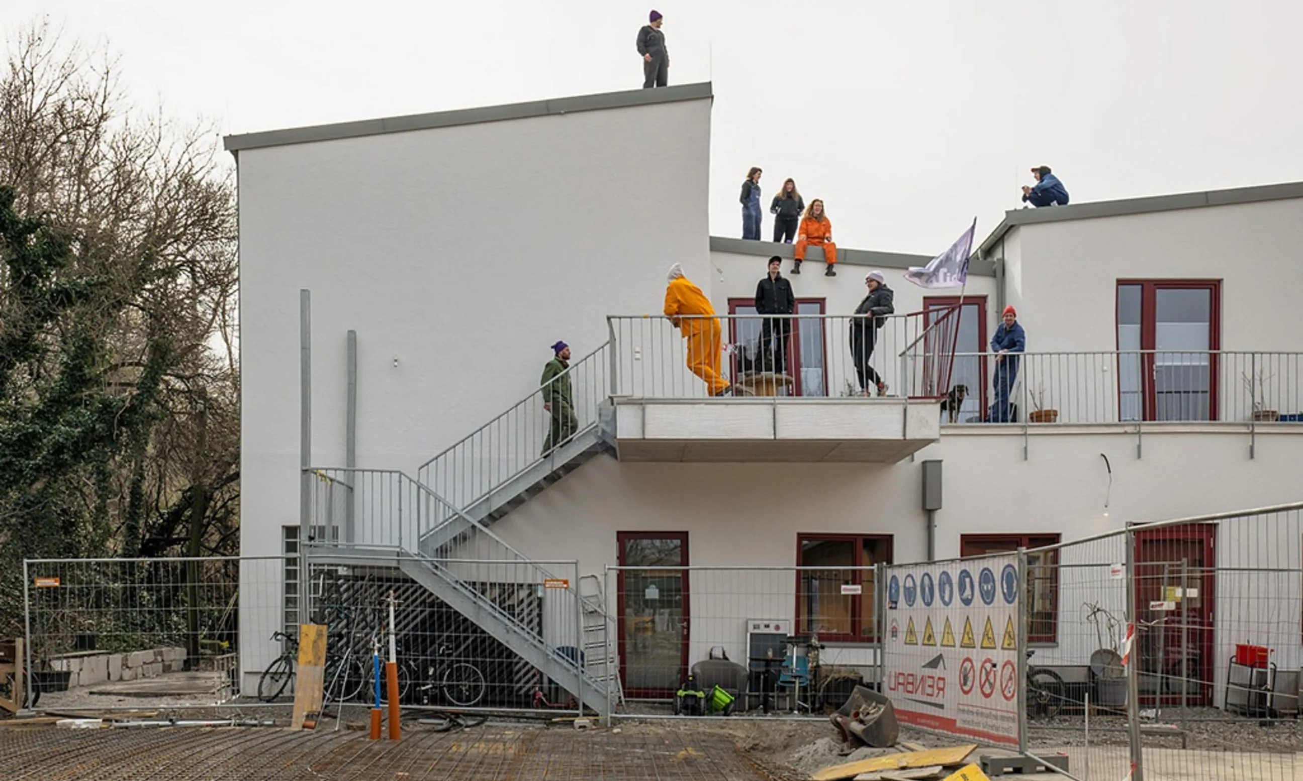 Bild eines zweigeschoßigen weißen Gebäudes mir Menschen in der Umgebung