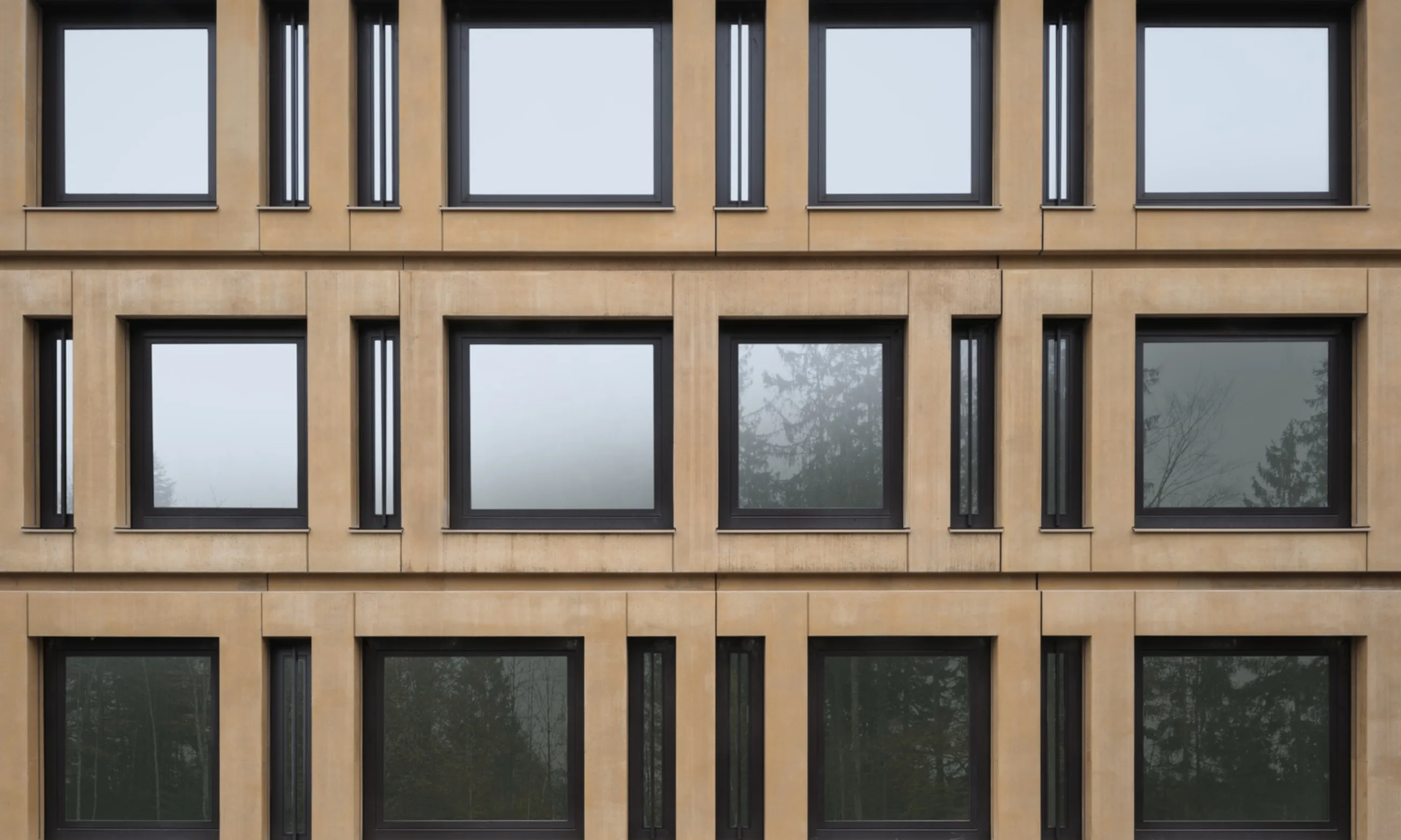 Photo einer braunen Sichtbetonfassade mit großen Fensteröffnungen