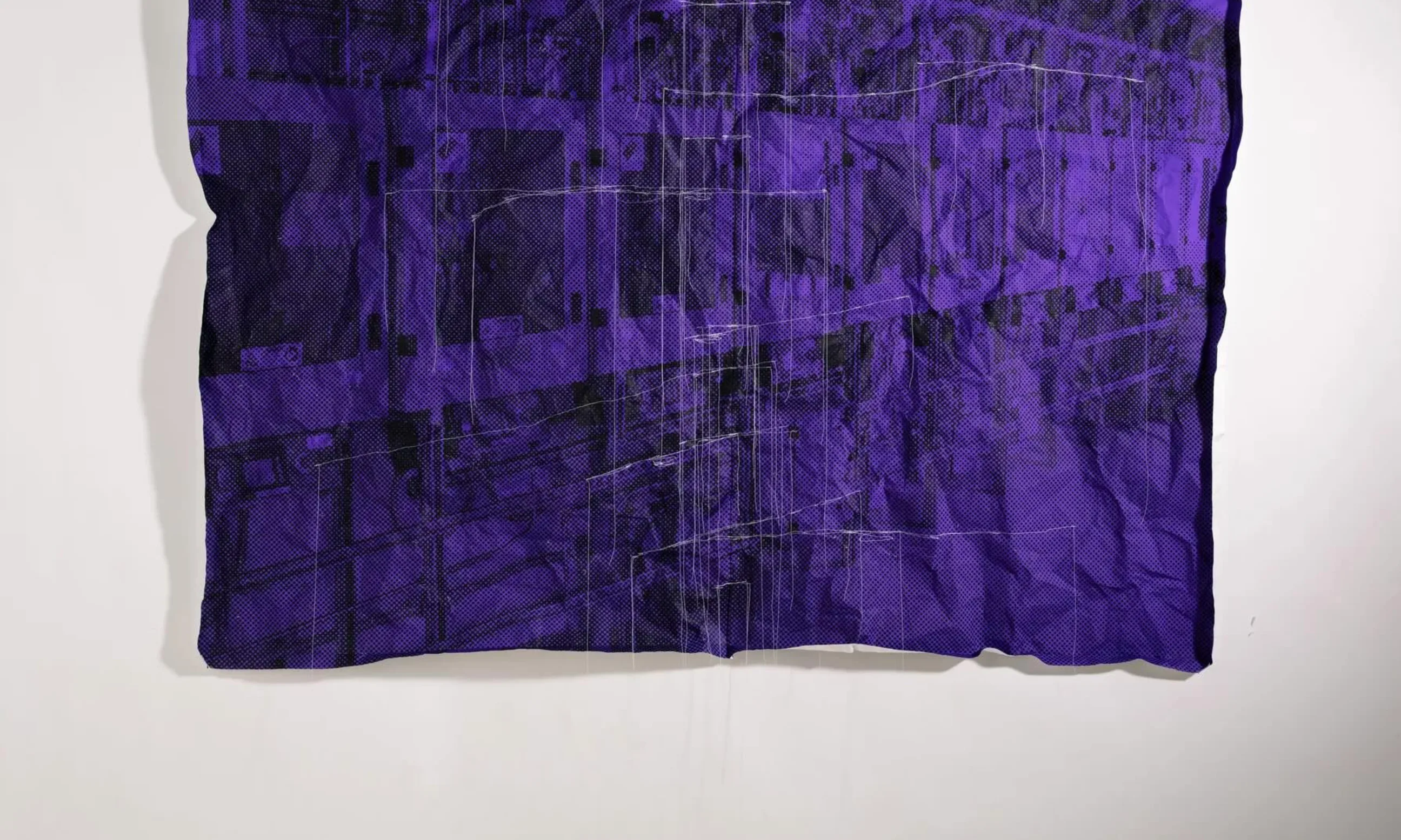 Eine violett-schwarze Plane auf einer weißen Wand hängend