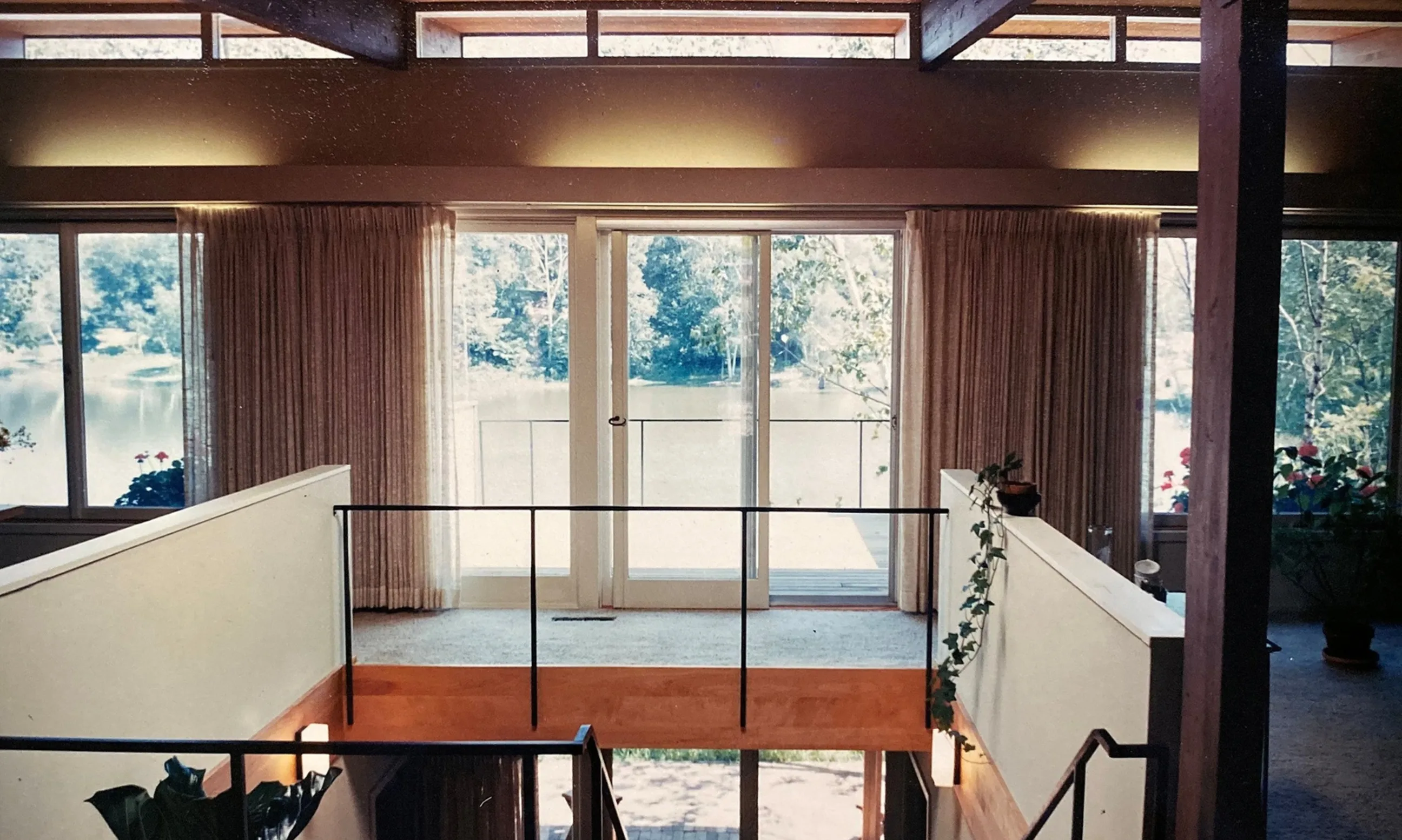 Bild eines zweigeschossigen Innenraums, im Mittelpunkt eine Treppe, im Hintergrund ein Fenster mit Blick nach Außen