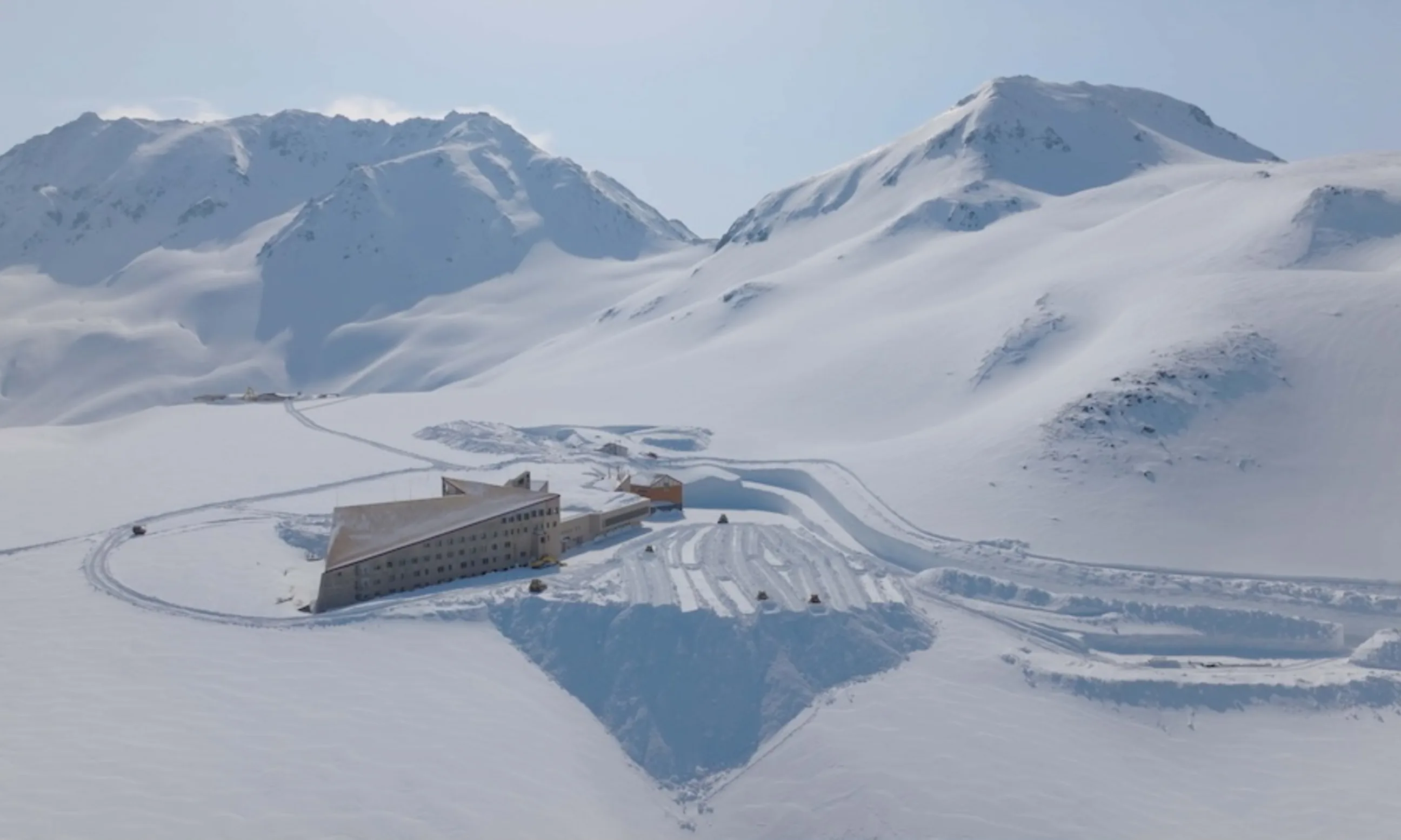 Luftaufnahme einer verschneiten Landschaft, im Bild mittig ein mehrgeschossiges Gebäude