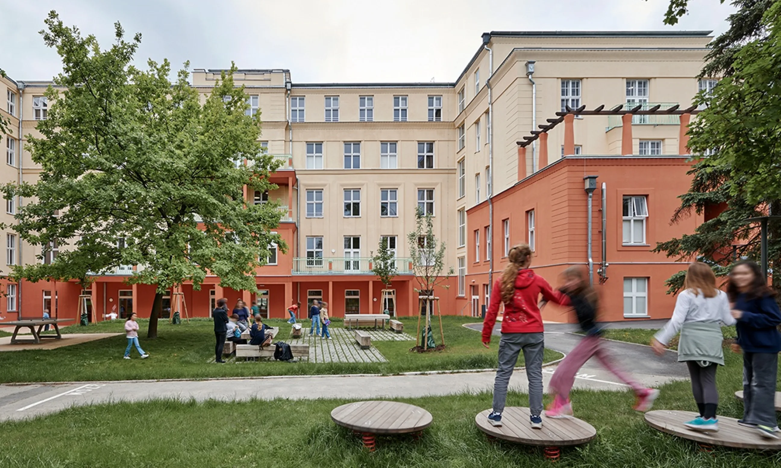 Bild eines Spielplatzes im Freien, im Hintergrund ein gelb-oranges Gebäude