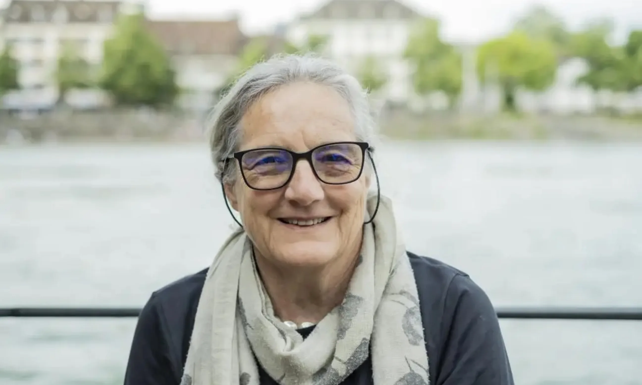 Porträt einer Frau, im Hintergrund eine Flusslandschaft