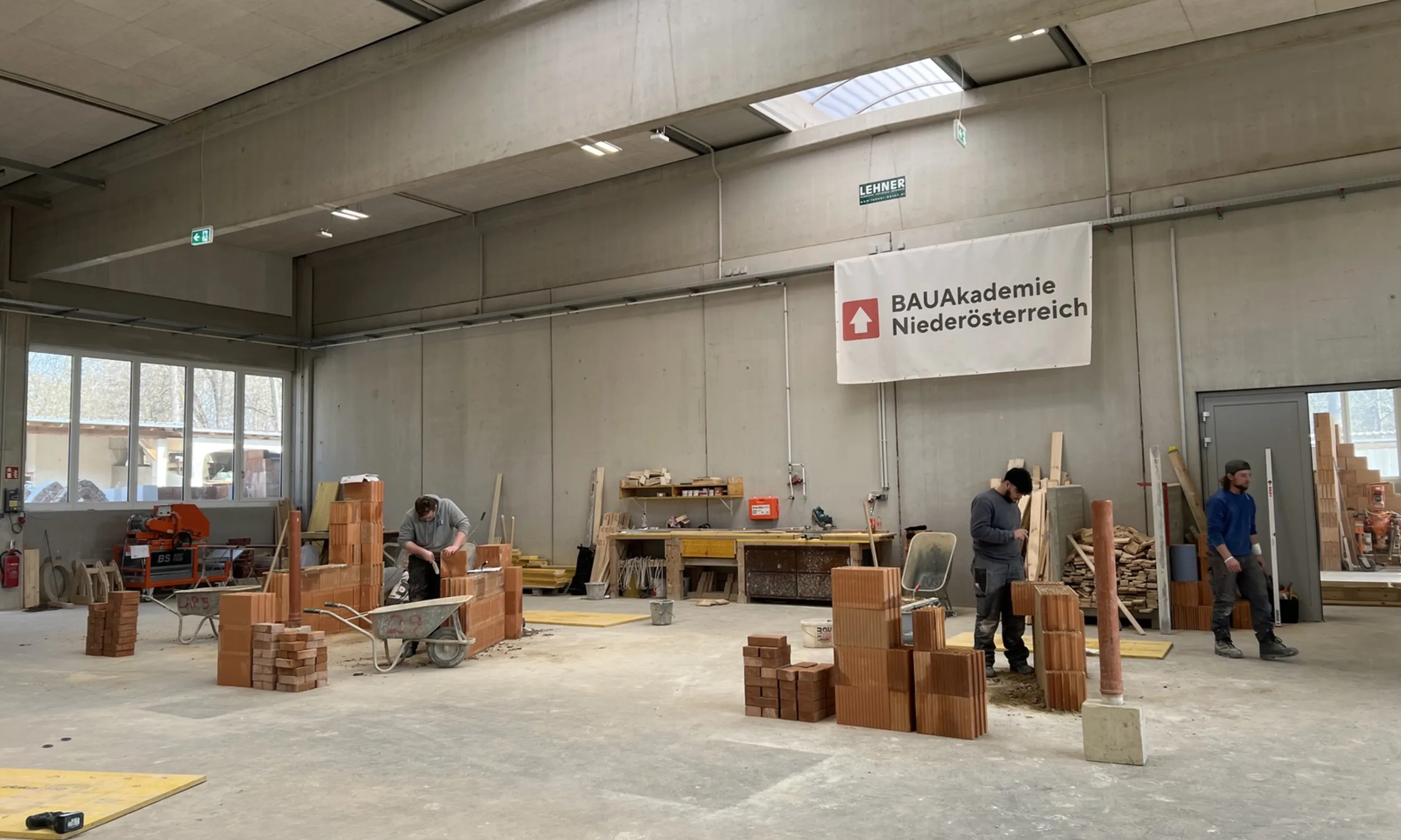 Zwei Menschen arbeiten in einer Halle an zwei Mauerwerken