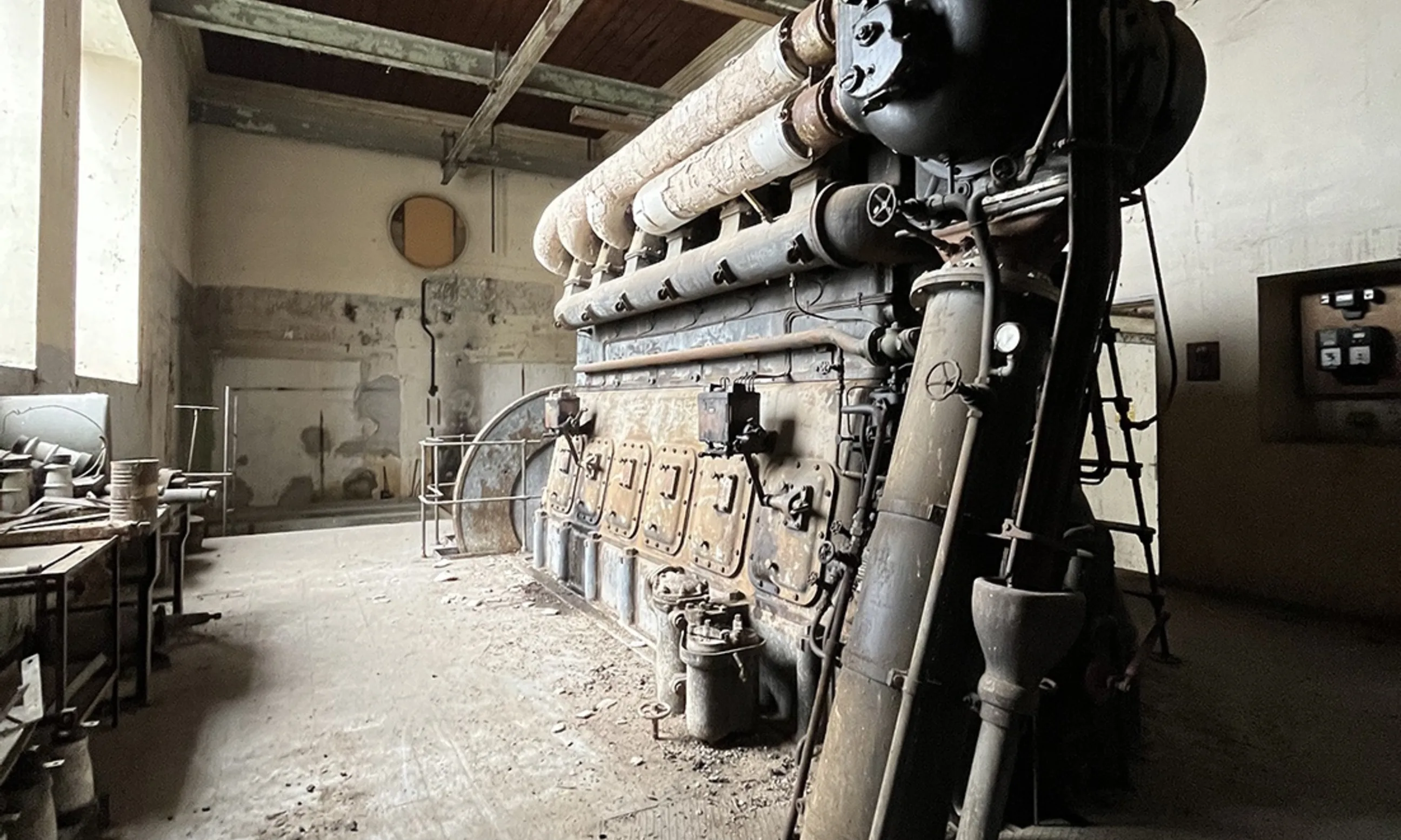 Eine große Maschine im Vordergrund, geschlossen in einer verstauben Halle
