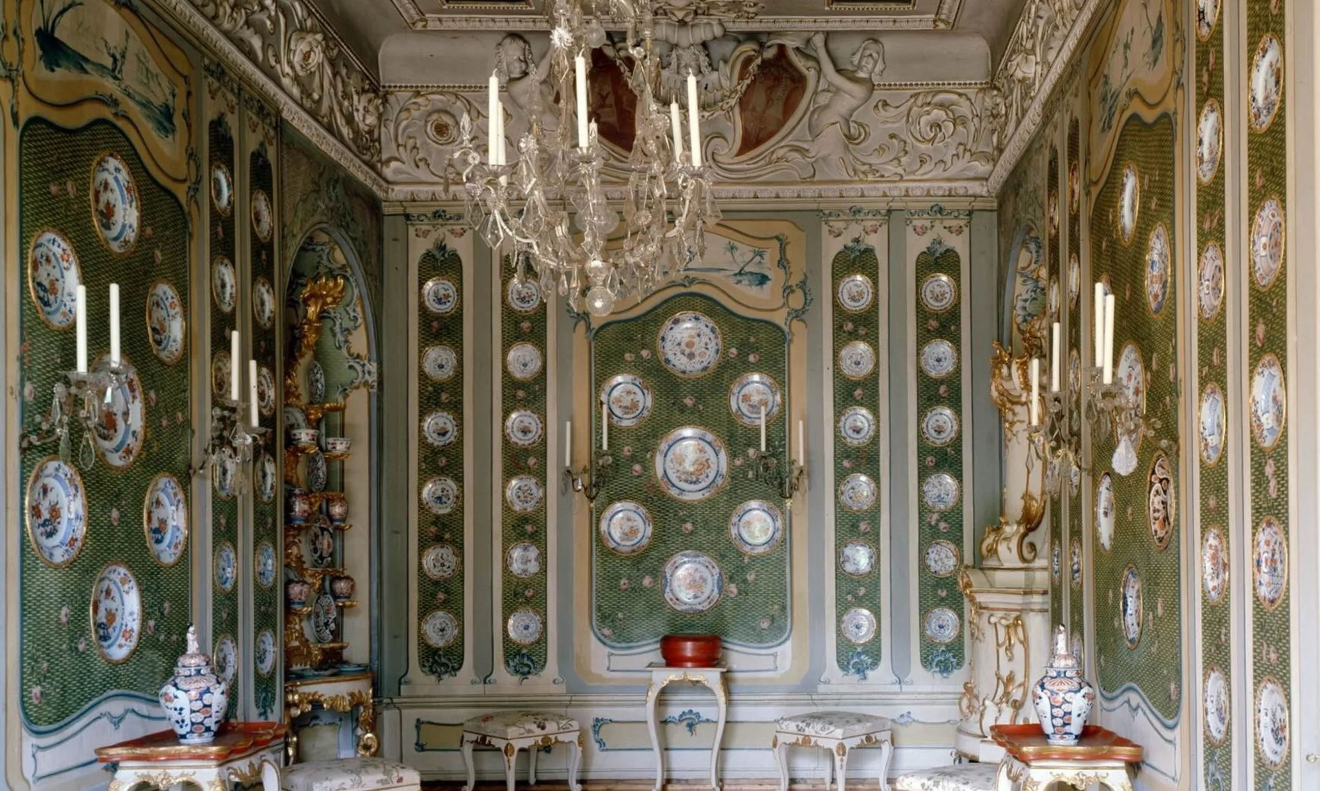 Foto eines grünen Raumes mit Luster in der Mitte und Porzellantellern auf den Wänden