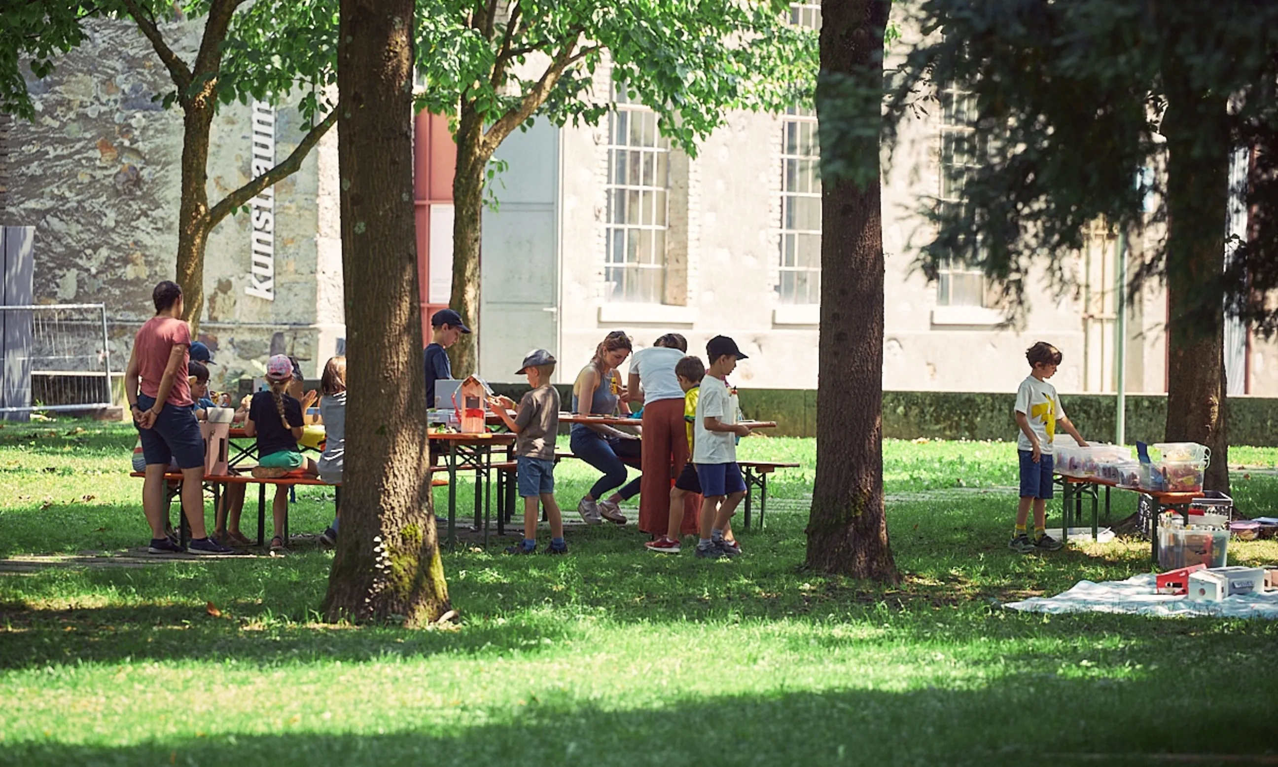 Photo einer Parkanlage mit vielen großen Bäumen, dazwischen spielen Kinder
