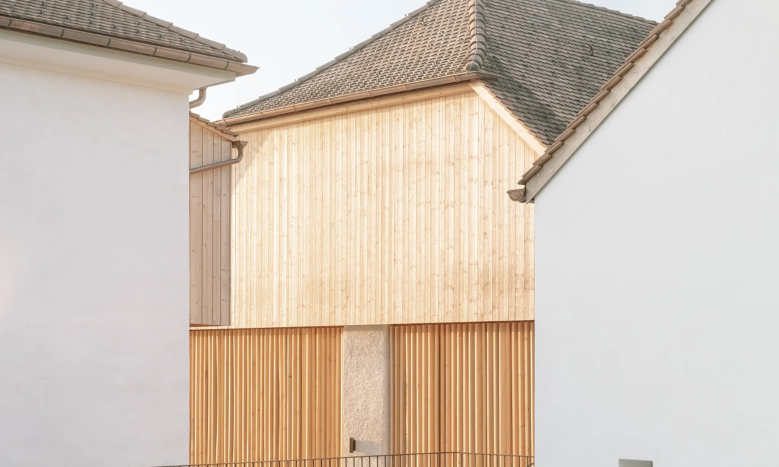Foto eines Gebäudes aus Holz zwischen zwei weißen Gebäuden